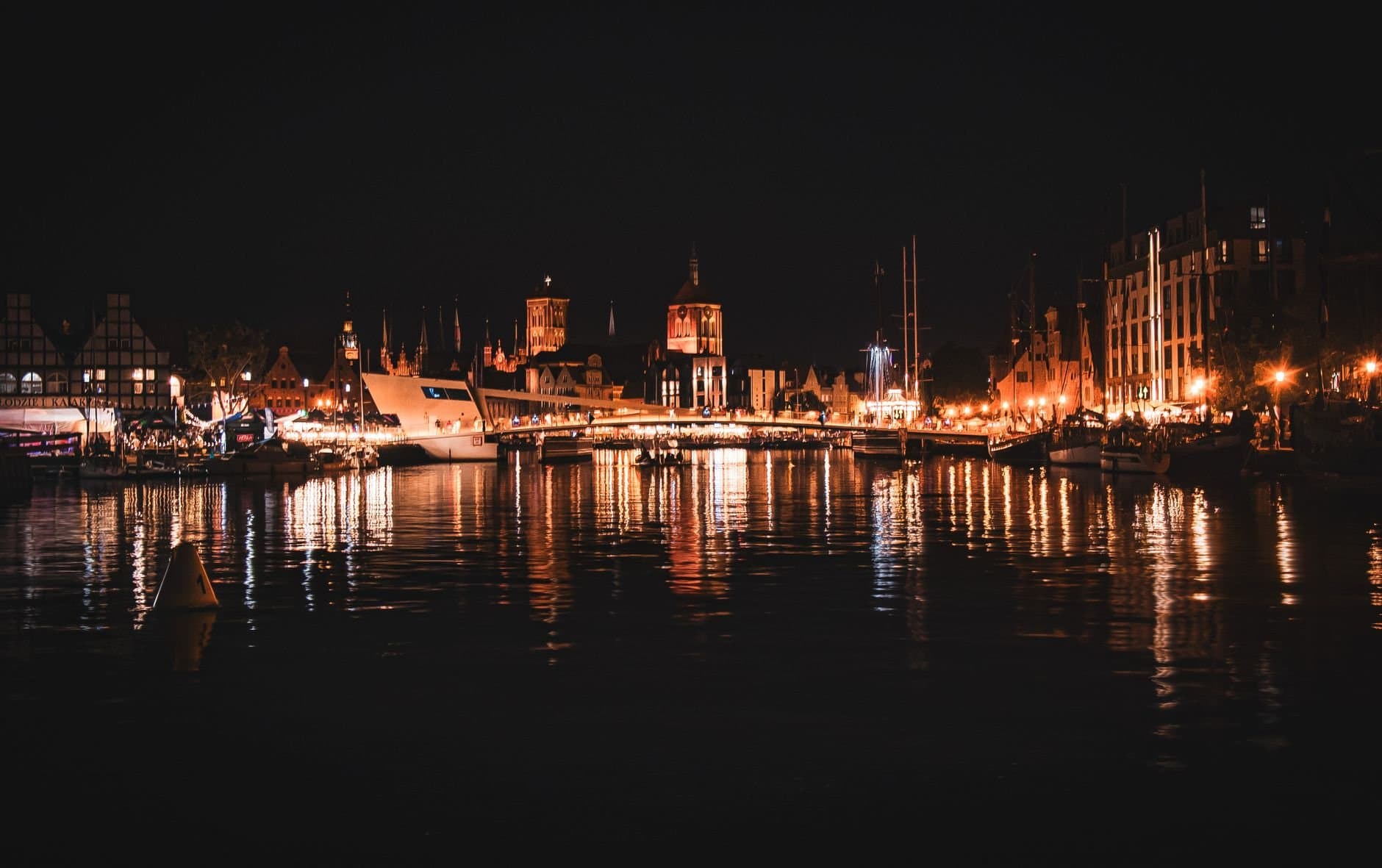 Stunning nighttime view of Gdańsk's old town with lights reflecting off the Motlawa River.
