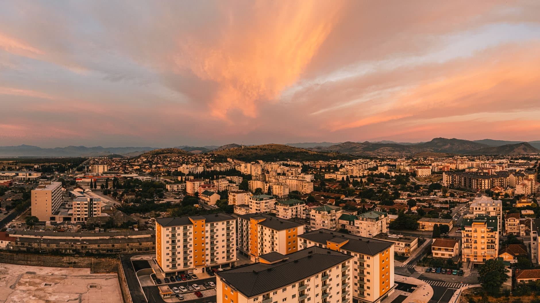 Scenic aerial view of Podgorica, Montenegro at sunset featuring vibrant skies and urban architecture.